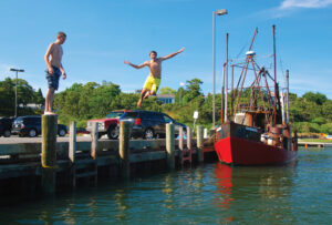 Kids have a blast jumping off the pilings of the Oyster Pond River Landing. Photo/Tom Richardson chatham-tr-kids-jumping-off-pier