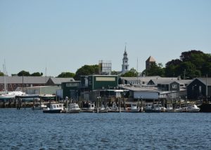Quohog boats line a dock with the town of Warren as a backdrop. warren-az-quohog-boats-town-skyline-700x500